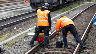 Zwei Gleisbauarbeiter auf einer Bahnstrecke