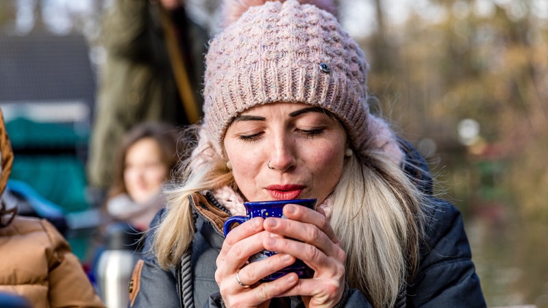 Eine Frau umklammert eine Glühwein-Tasse.