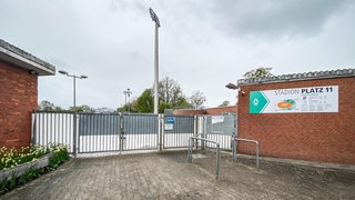 Blick auf das verschlossene Tor am Stadion Platz 11 vor dem Weser-Stadion bei dunkler Wolkendecke.
