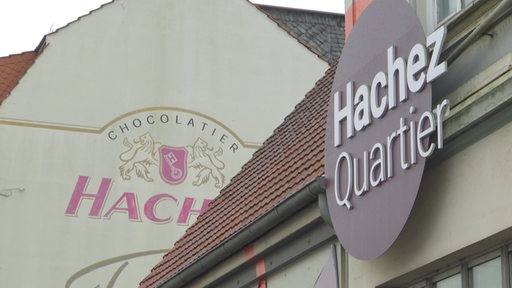 Ein Gebäude von außen und das "Hachez Quartier"-Logo zu sehen.