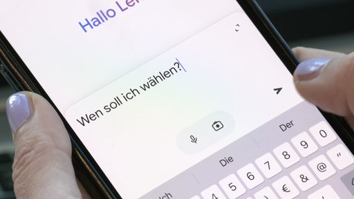 Auf einem Smartphone wird die Frage "Wen soll ich wählen" an einen Chatbot einer künstliche Intelligenz gestellt.