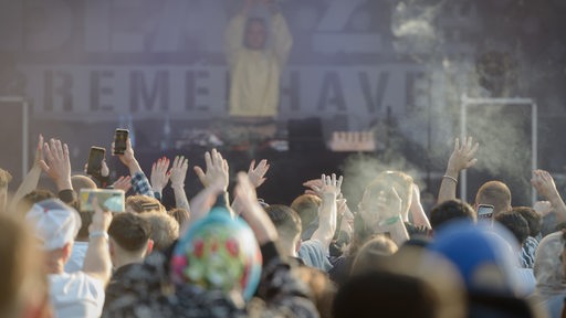 Bühne des Haven Beatz in der Stadthalle Bremerhaven. Davor feierne Menschen mit dem Rücken zur Kamera, die Hände zum Klatschen in den Himmel gestreckt.