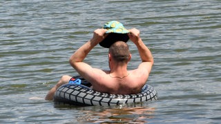 Ein Mann lässt sich in einem Schwimmring auf einem See treiben.