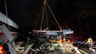 Kran hebt zerstörten Lkw von den Gleisen