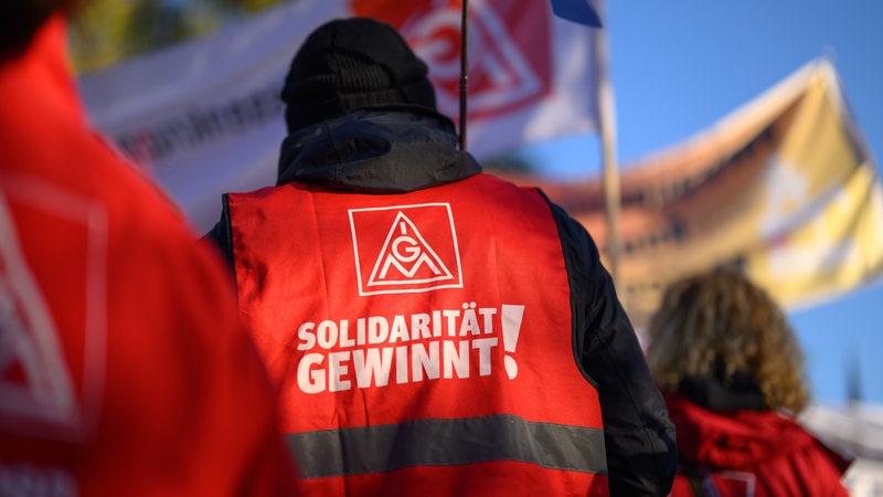 Eine Person auf einer Demo trägt eine rote Weste mit der Aufschrift: "Solidarität gewinnt".