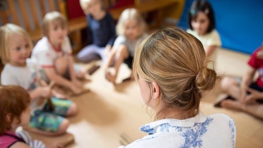 Eine Frau sitzt vor mehreren Kindern