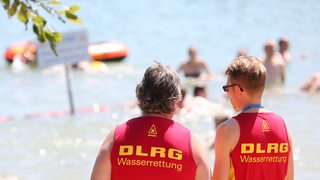 Zwei Retter der DLRG überwachen einen Badestrand.