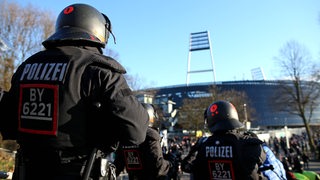 Schwarz-gekleidete Polizisten mit Helmen stehen in der Fanmenge vor dem Weser-Stadion.