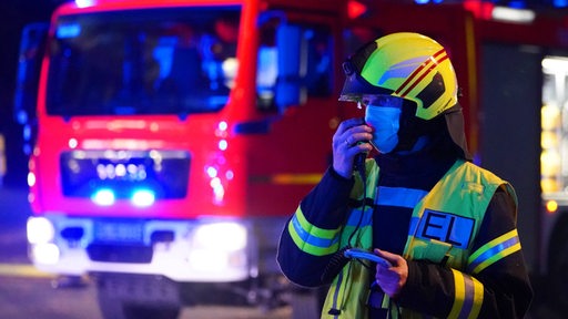 Feuerwehrfahrzeug und Mann bei Nacht (Symbolbild)