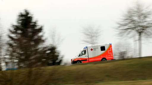 Ein Krankenwagen fährt eine Landstraße entlang.