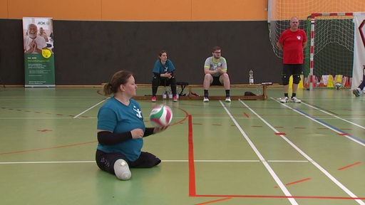 Bremerin sitzt auf Boden und hält einen Volleyball