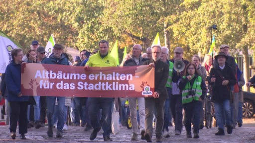 Eine Gruppe von Personen steht während einer Demonstration hinter einem Banner