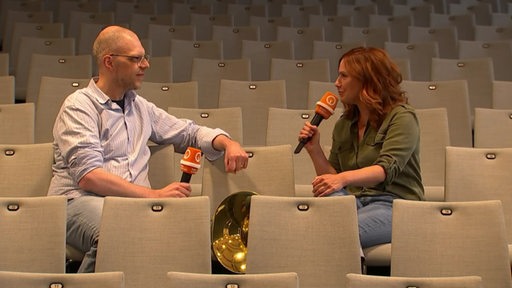 Die Reporterin Katja Runge interviewt den Solo-Hornist Matthias Berkel.