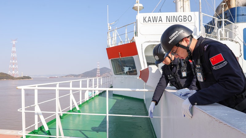 Männer stehen an der Reling eines Schiffes.