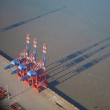 Luftaufnahme: Drei Containerbrücken am Jade-Weser-Port werfen ihren Schatten auf den Jadebusen. 