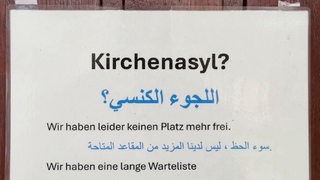 Ein Schild mit Text hängt an einer Holztür.