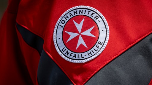 Das Logo der Johanniter-Unfall-Hilfe ist auf einer roten Jacke zu sehen.