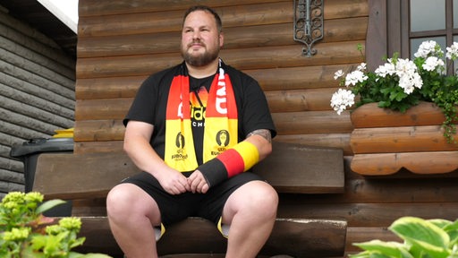 Der Fussballfan Kai Flathmann mit einem in Deutschlandfarben vergipstem Arm.