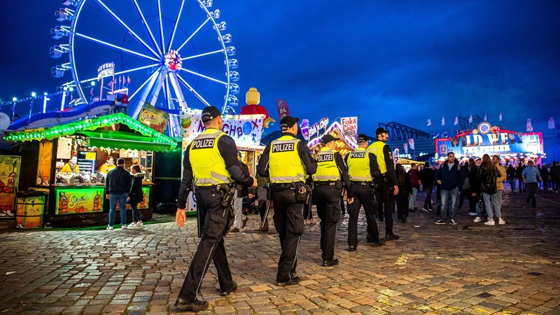 Polizisten laufen über die Bürgerweide, auf der der Bremer Freimarkt stattfindet.