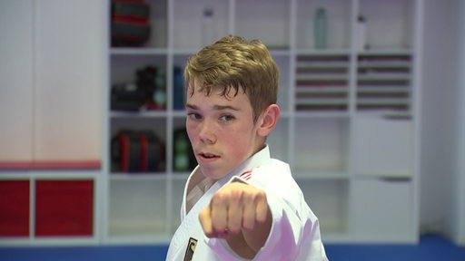 Der Karateka Alexander Albien streckt seinen Arm mit einer geschlossenen Faust nach vorne.