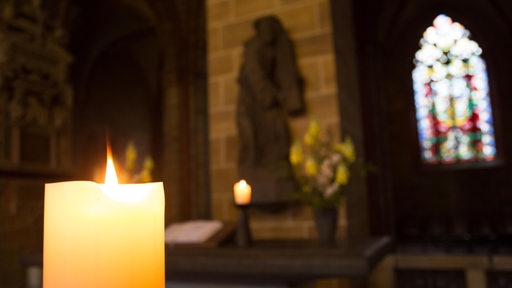 Eine Kerze brennt am Nebenaltar im St.-Petri-Dom