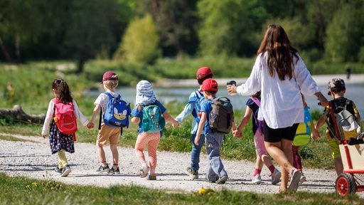 Eine Kindergartengruppe macht einen Ausflug an einen Fluss.