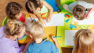 Kinder im Kindergartenaltersitzen meiner Erziehung an einem Tisch und basteln (Symbolbild)