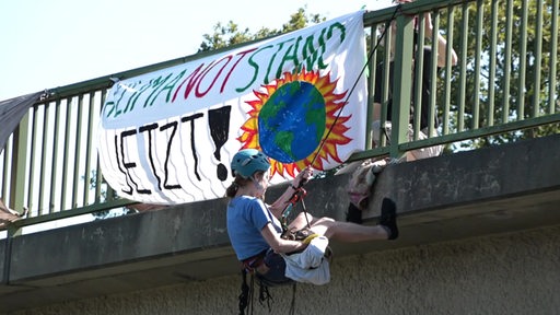 Eine Klimaaktivistin seilt sich von einer Brücke ab