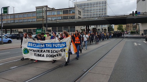 Menschen laufen bei einer Demonstration in Bremen auf einer Straße.