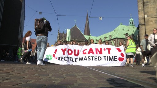 Demonstrierende von Fridays for Future halten ein Banner während sie den Bremer Marktplatz entlanggehen