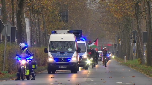 Zwei Polizeibusse, die eine Kolonne Anführen.