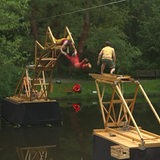 Menschen hangeln sich über eine Holzbrücke