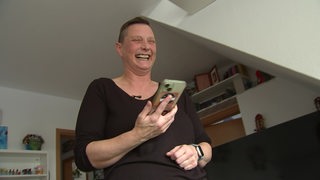 Eine Frau telefoniert bei sich zu Hause und lacht