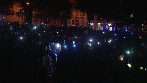 Menschen sitzen mit bunten Lichtern in der Dunkelheit