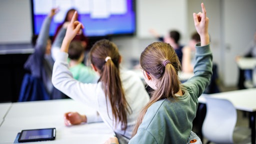 Schüler sitzen in einem Klassenzimmer und melden sich.