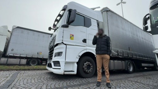 Der LKW-Fahrer Robert vor auf einem Rastplatz vor seinem Fahrzeug