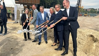 Beim symbolischen Spatenstich für den Lürssen-Campus halten zwei Frauen und vier Männer ihre Spaten in die Höhe.