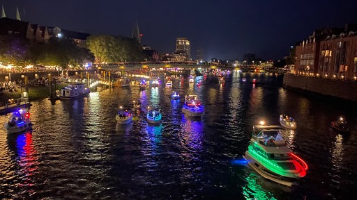 Boote fahren mit bunten Lichtern geschmückt an der Schlachte die Weser entlang.