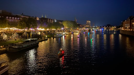 Boote fahren mit bunten Lichtern geschmückt an der Schlachte die Weser entlang.