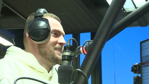 Werderspieler Marvin Duksch sitzt im Hörfunkstudio von Radiobremen und gibt ein Interview. 