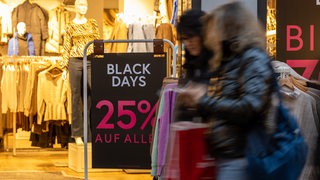 Kundinnen vor einem Geschäft, das mit Black-Friday-Rabatte wirbt (Archivbild)