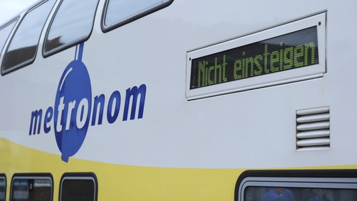 Ein Zug mit dem Logo "Metronom" und einer Digitalanzeige, die "Nicht einsteigen" anzeigt.