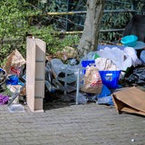Illegal abgeladener Müll Sperrmüll liegt neben einem überfüllten Mülleimer auf einem Parkplatz
