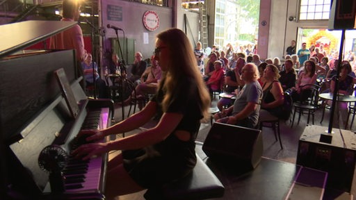 Ein kleines Konzert, dem einige Besucher zuschauen und zuhören.