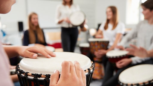 Im Musikunterricht sitzen die Schüler im Kreis und trommeln auf verchiedenen Instrumenten.