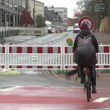 Eine Fahrradfahrerin steht vor der Baustelle der neuen Radpremiumroute Wallring. 