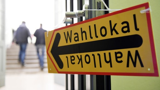 Ein Schild mit der Aufschrift "Wahllokal" hängt an einer geöffneten Tür.