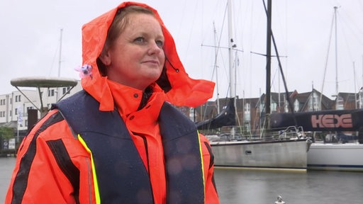Die Kapitänin Nicole Schneiders in einer orangefarbenen Regenjacke während einer Hafenrundfahrt.