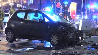 Ein beschädigtes Auto steht an einem Bahnübergang.