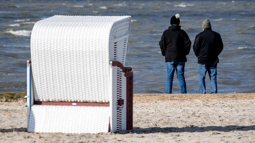 Zwei Personen stehen bei rauhem Wetter an einem Nordsee-Strand.
